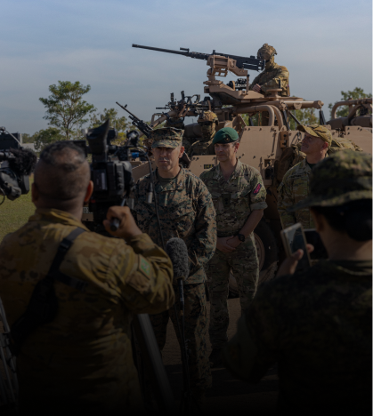 A group of soldiers are standing in front of a military vehicle