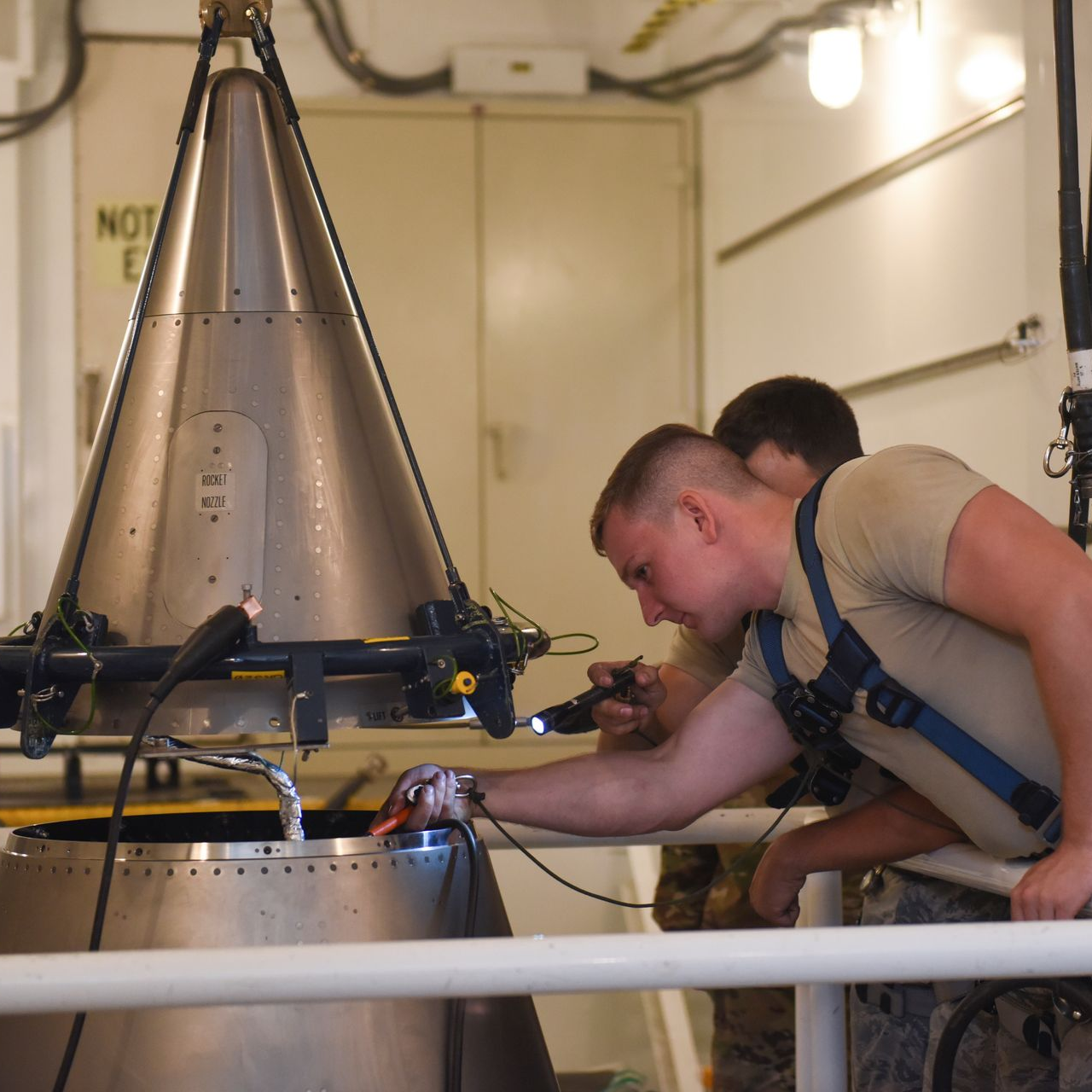 A man in a camo uniform is typing on a laptop