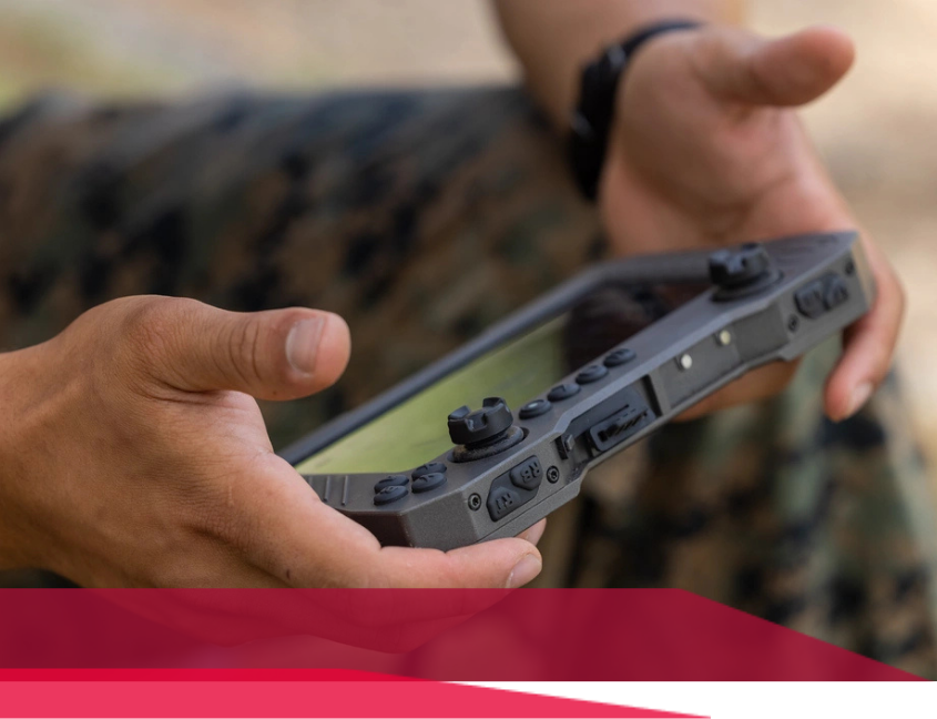 Person holding a rugged, gray tablet with buttons, outdoors.