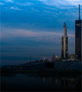 A rocket is sitting in front of a building with a blue sky in the background