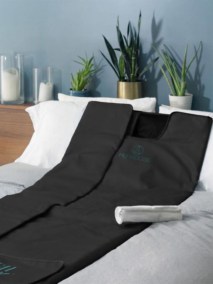Black compression leg wrap on a bed. Plants and a cabinet are in the background.