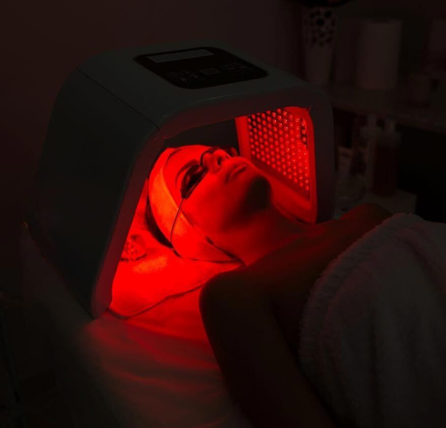 Woman receiving red light therapy treatment on a spa bed, wearing a towel.