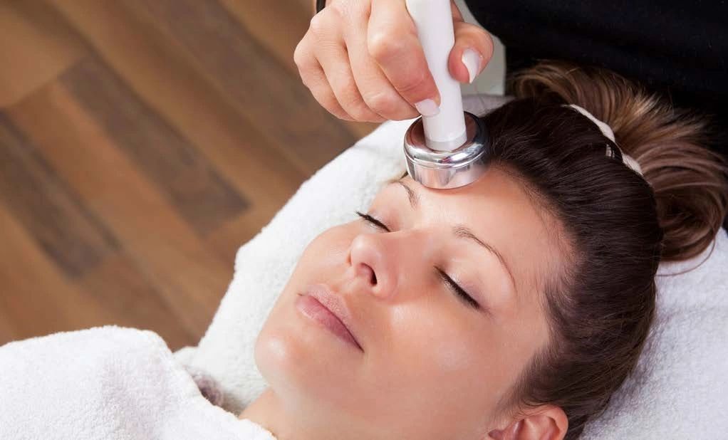 Woman receiving a facial treatment, a device is used on her forehead.