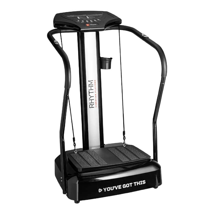 Black and silver whole-body vibration machine with handrails and a control panel, in a home setting.