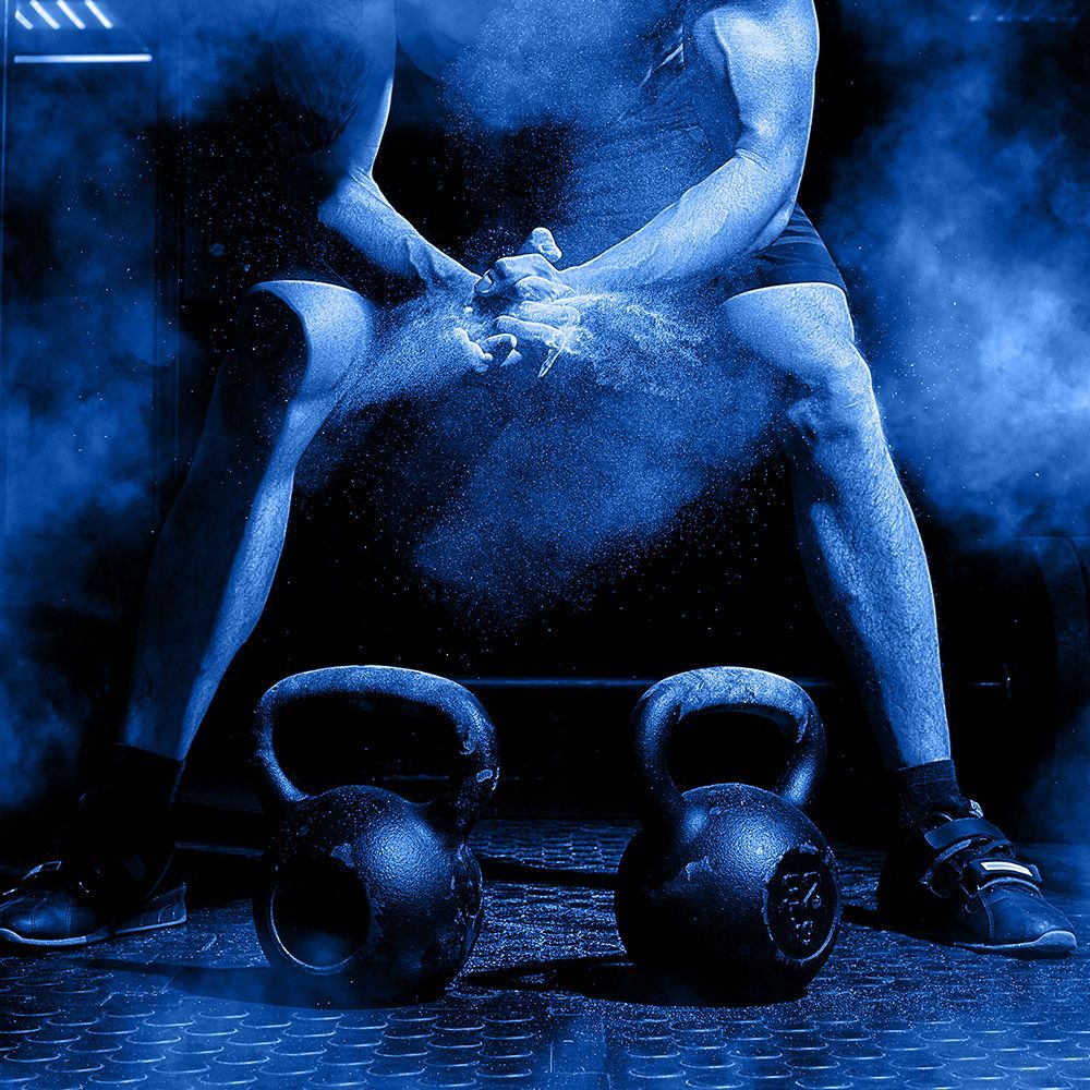 A man is sitting on a bench with kettlebells in front of him