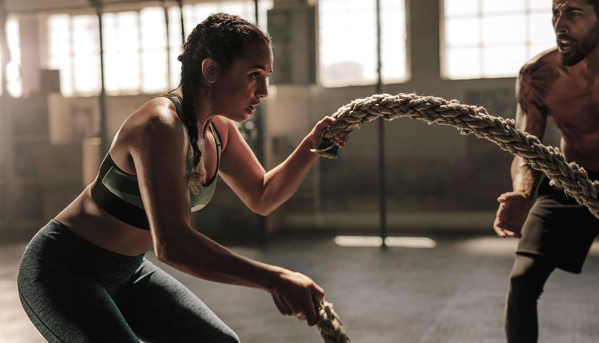 A man and a woman are playing with ropes in a gym.