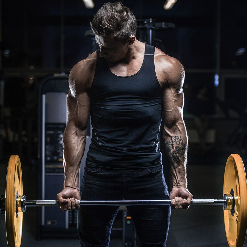 A man and a woman are doing lunges in a gym.