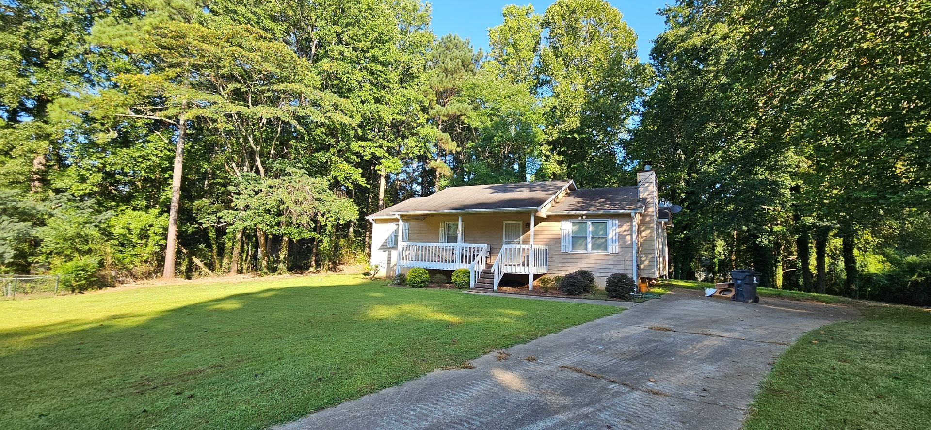 A house with a driveway leading to it is surrounded by trees.