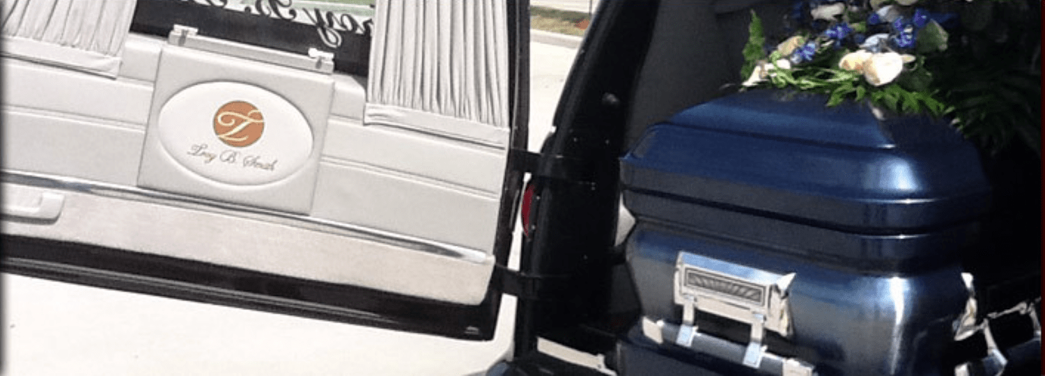 Black luggage bag with flowers beside a silver vehicle door with a circular logo sticker