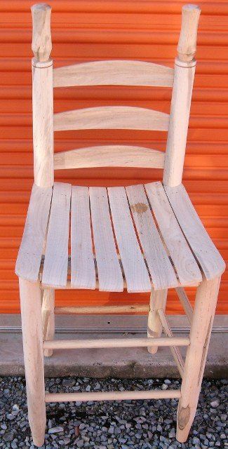 A wooden chair is sitting in front of an orange wall