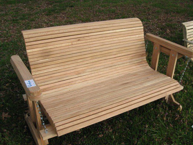 A wooden swing is sitting on top of a lush green field.