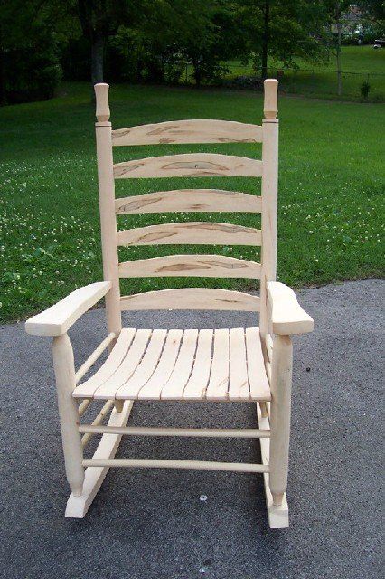 A wooden rocking chair is sitting on the side of a road