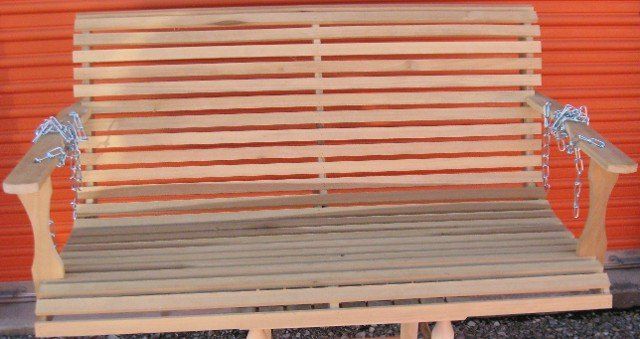 A wooden swing is sitting in front of an orange wall.