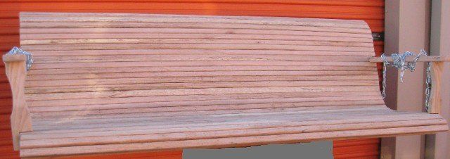 A wooden bench is sitting in front of a red wall.