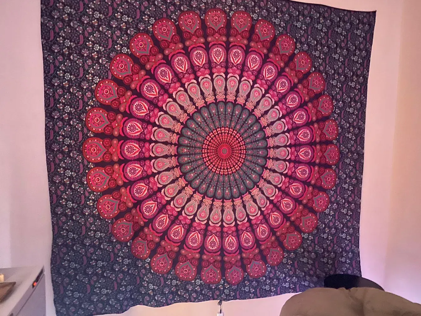 Purple-and-pink mandala tapestry hanging on a wall above a bed