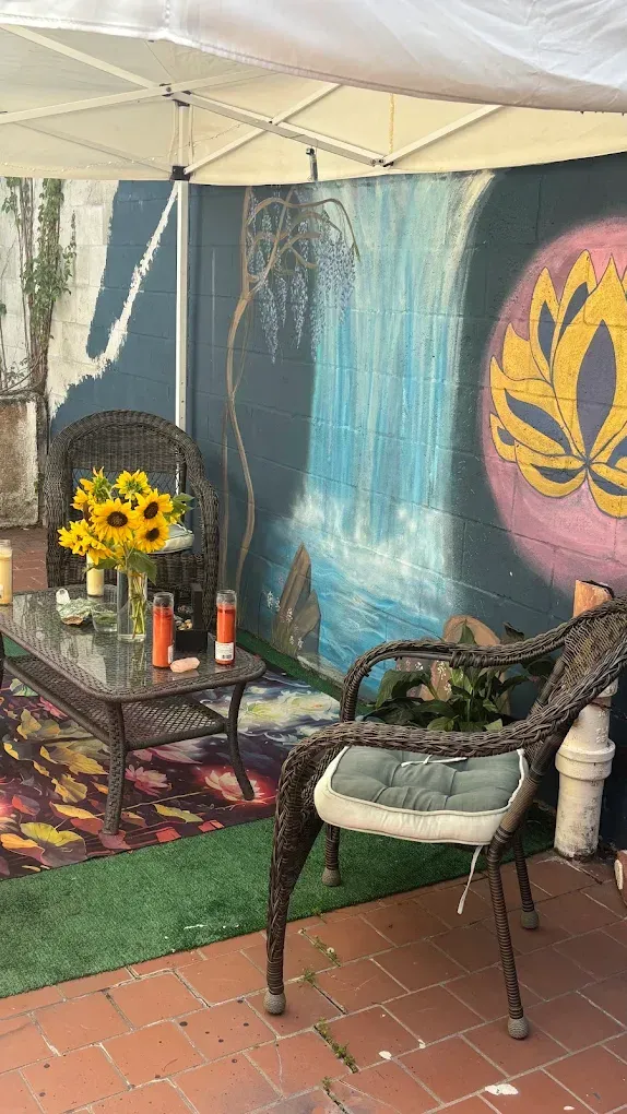 Outdoor patio shrine with candles, sunflowers, and a decorative wall mural under a canopy
