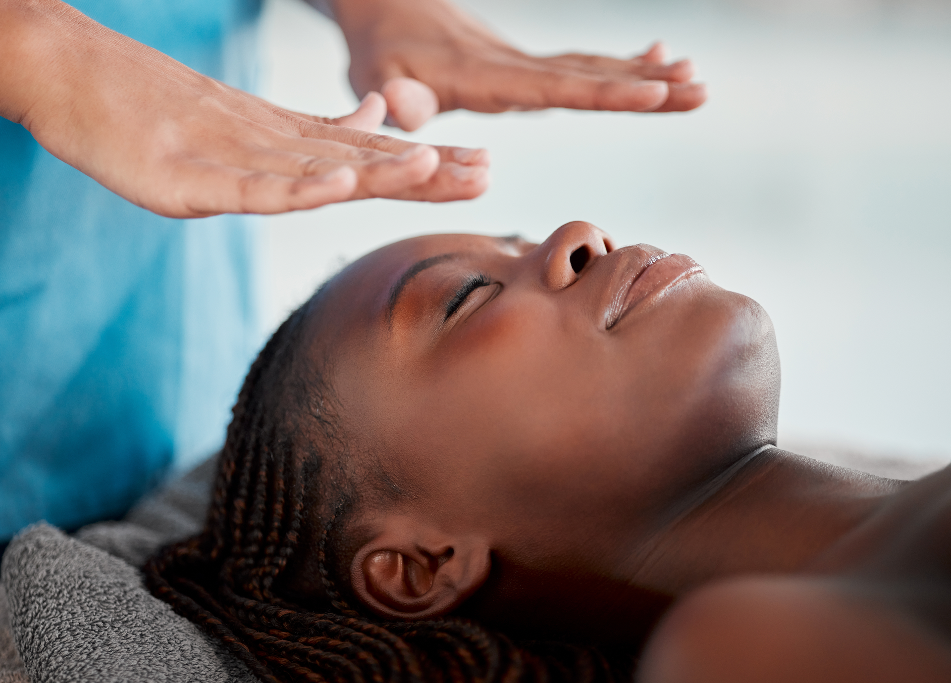 A woman is getting a healing massage with her eyes closed.