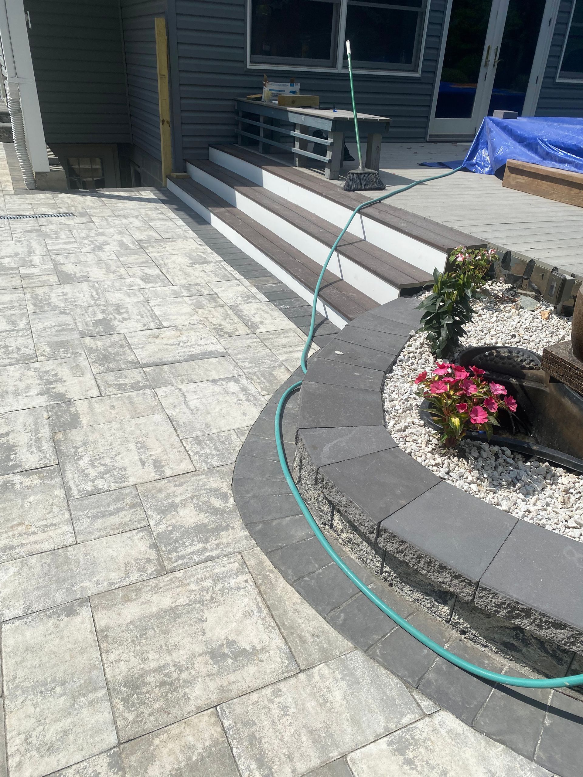 A hose is hanging from the side of a patio next to a set of stairs.