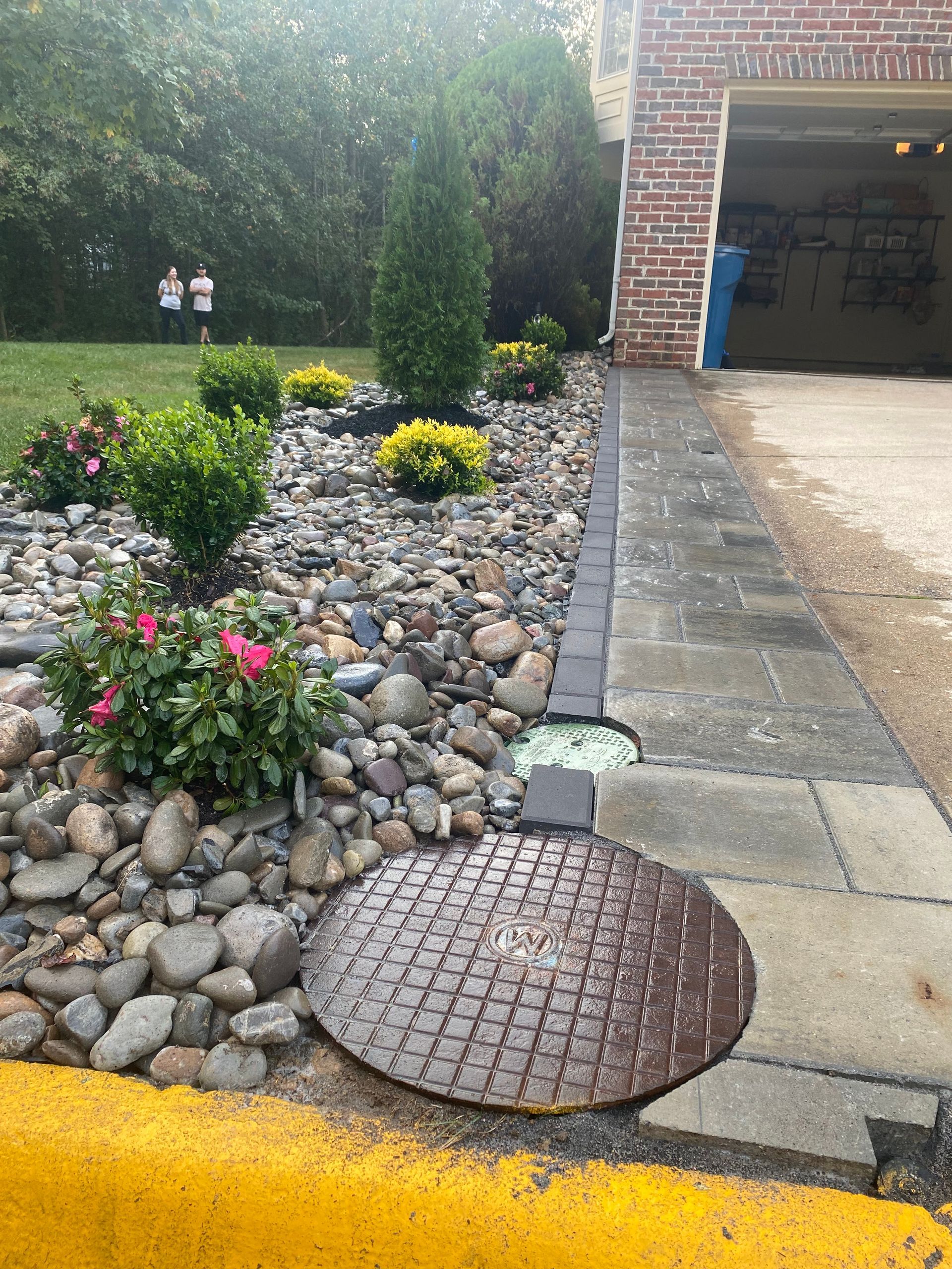 A manhole cover is sitting on the sidewalk in front of a house.