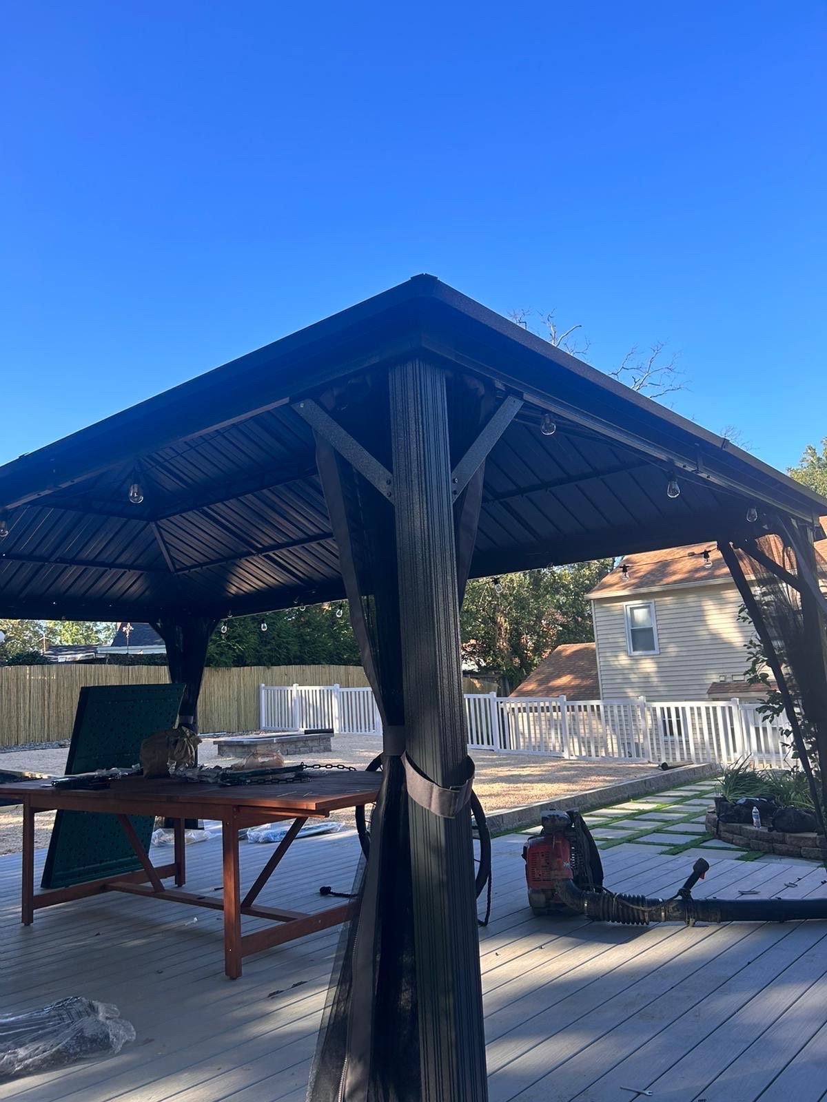 A gazebo on a deck with a table underneath it