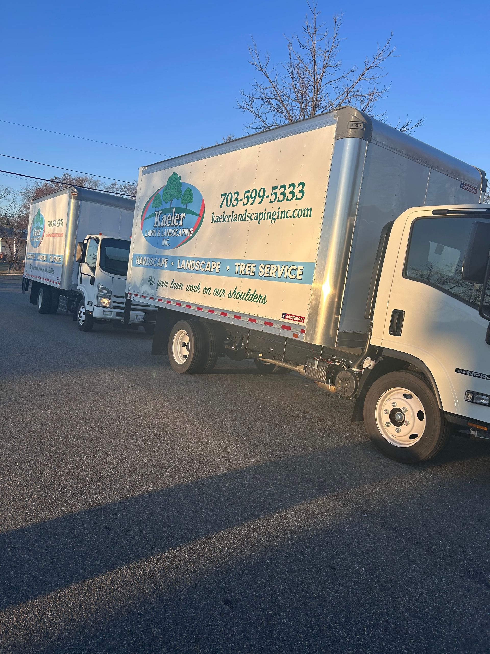 Two moving trucks are parked next to each other in a parking lot.