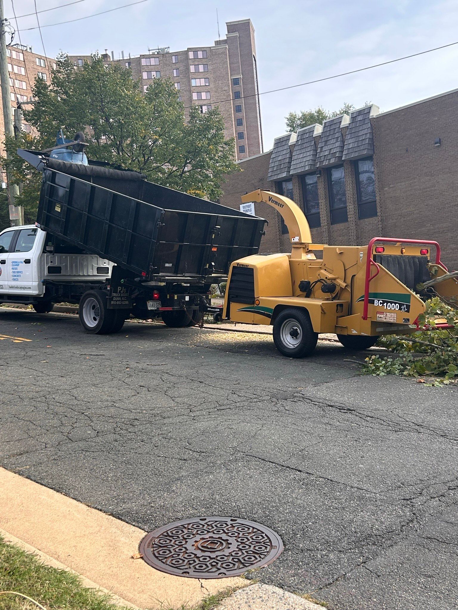 A truck and a tree chipper are parked on the side of the road.
