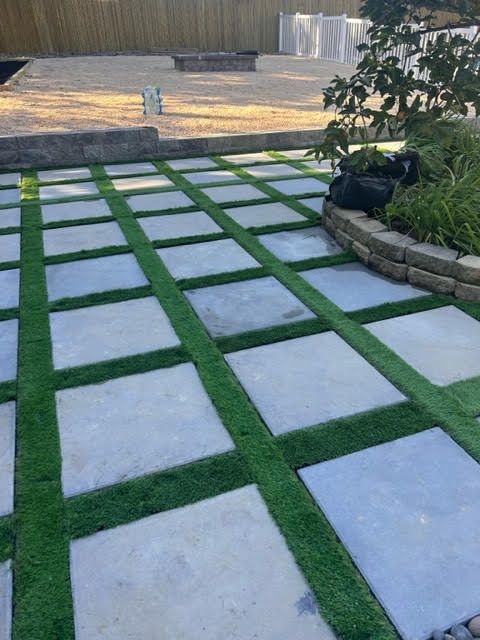 A patio with a lot of square tiles and grass.