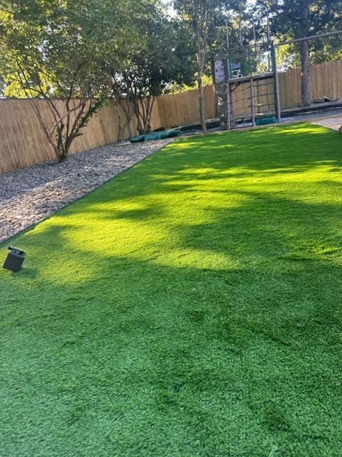 A lush green lawn with a wooden fence in the background.