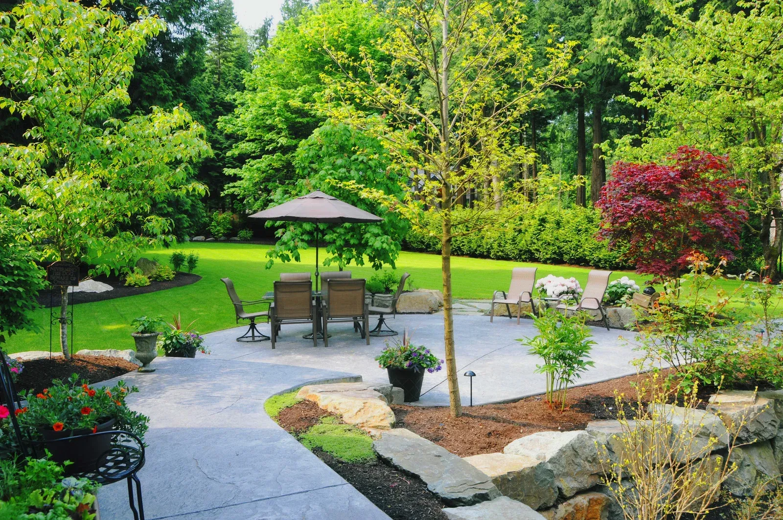 A well-landscaped backyard with a patio, seating area, and lush greenery.