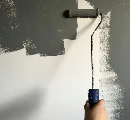 A person is using a paint roller to paint a wall