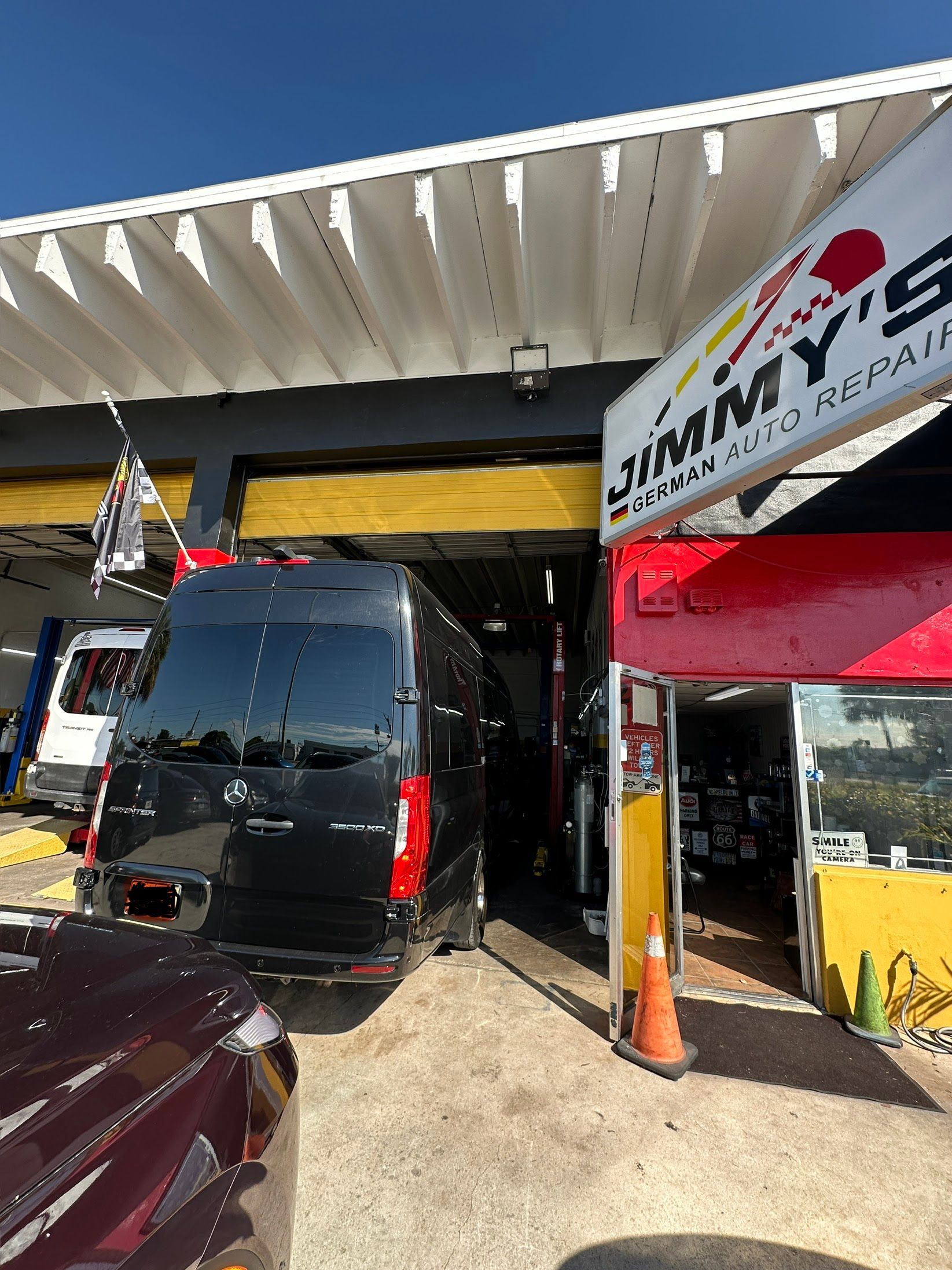 Black van inside a garage at Jimmy's Auto Repair. Red sign and yellow accents | Jimmy's German Auto Repair