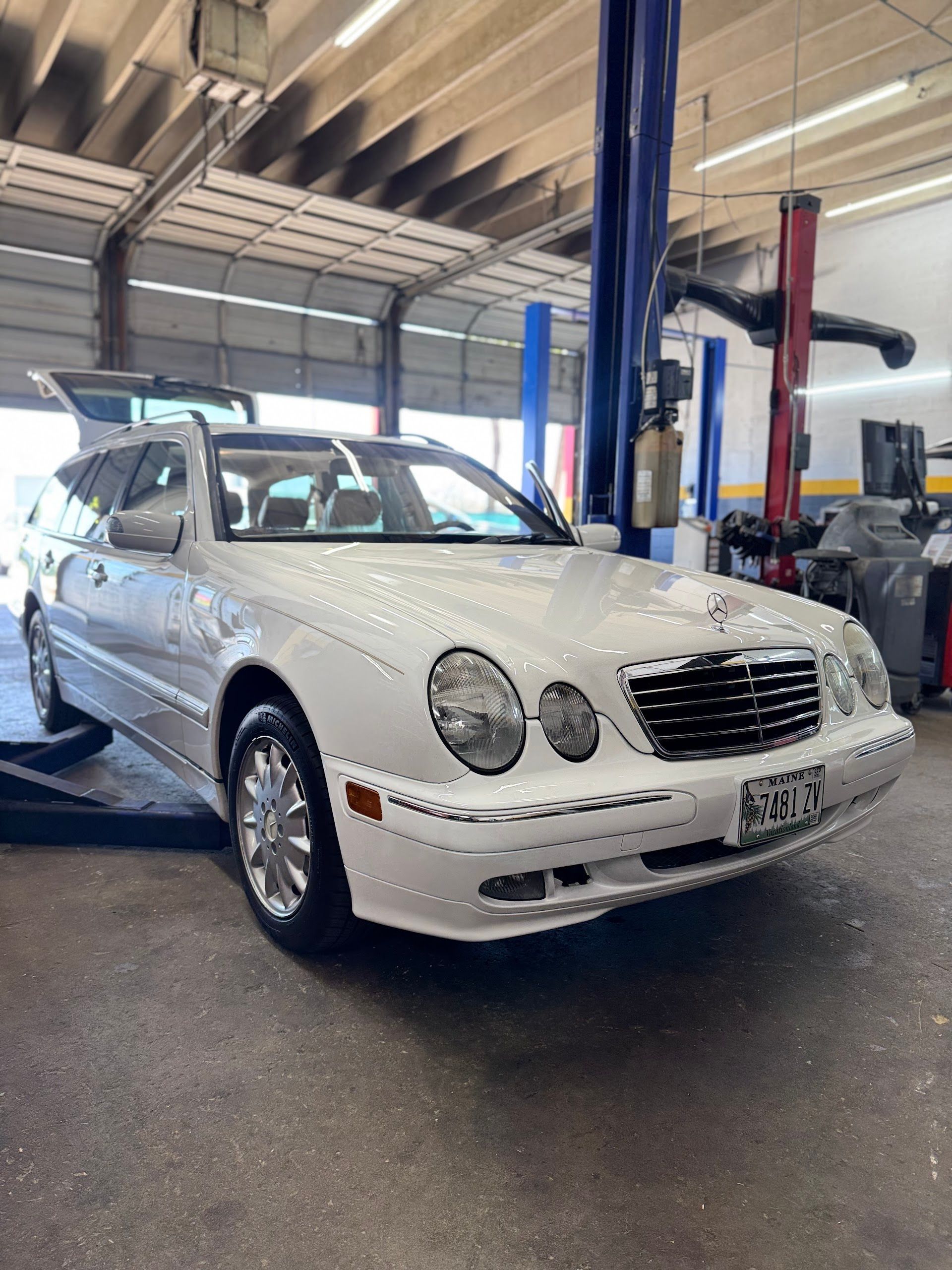 White Mercedes-Benz E-Class wagon inside a garage with its trunk open. | Jimmy's German Auto Repair