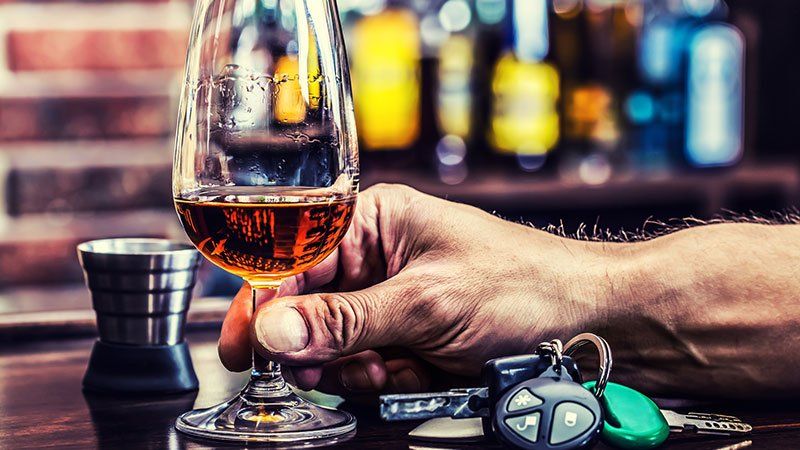 man drinking alcohol with car keys on table