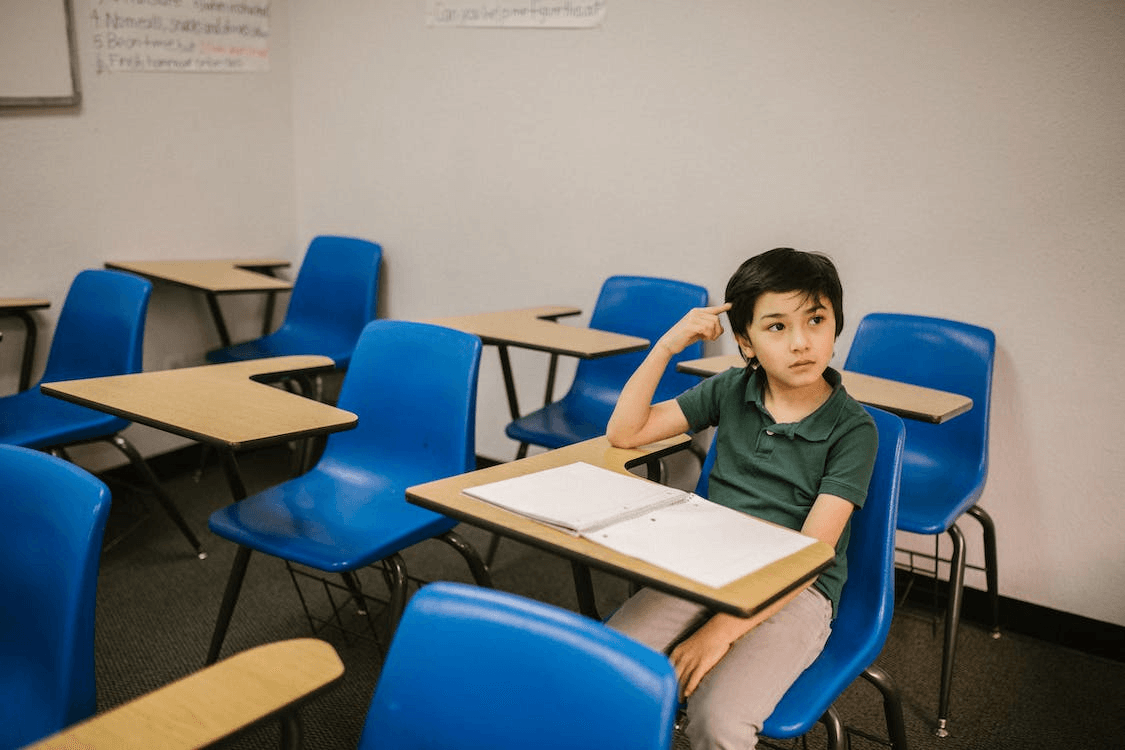 a young boy sitting in an empty classroom