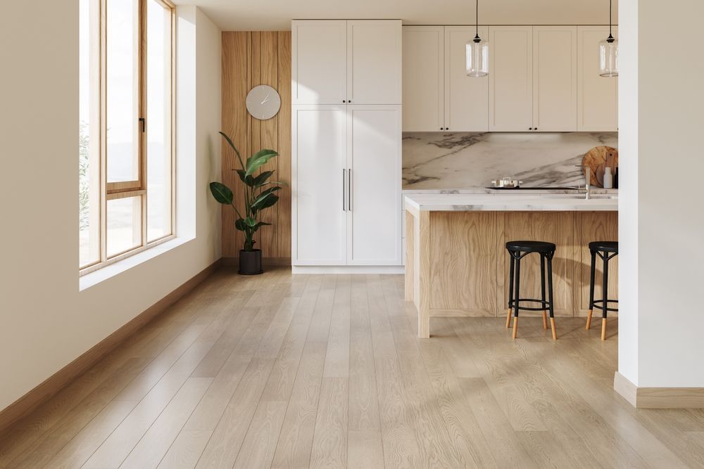 Modern kitchen with white cabinets, wood island, bar stools, and a potted plant by a large window.