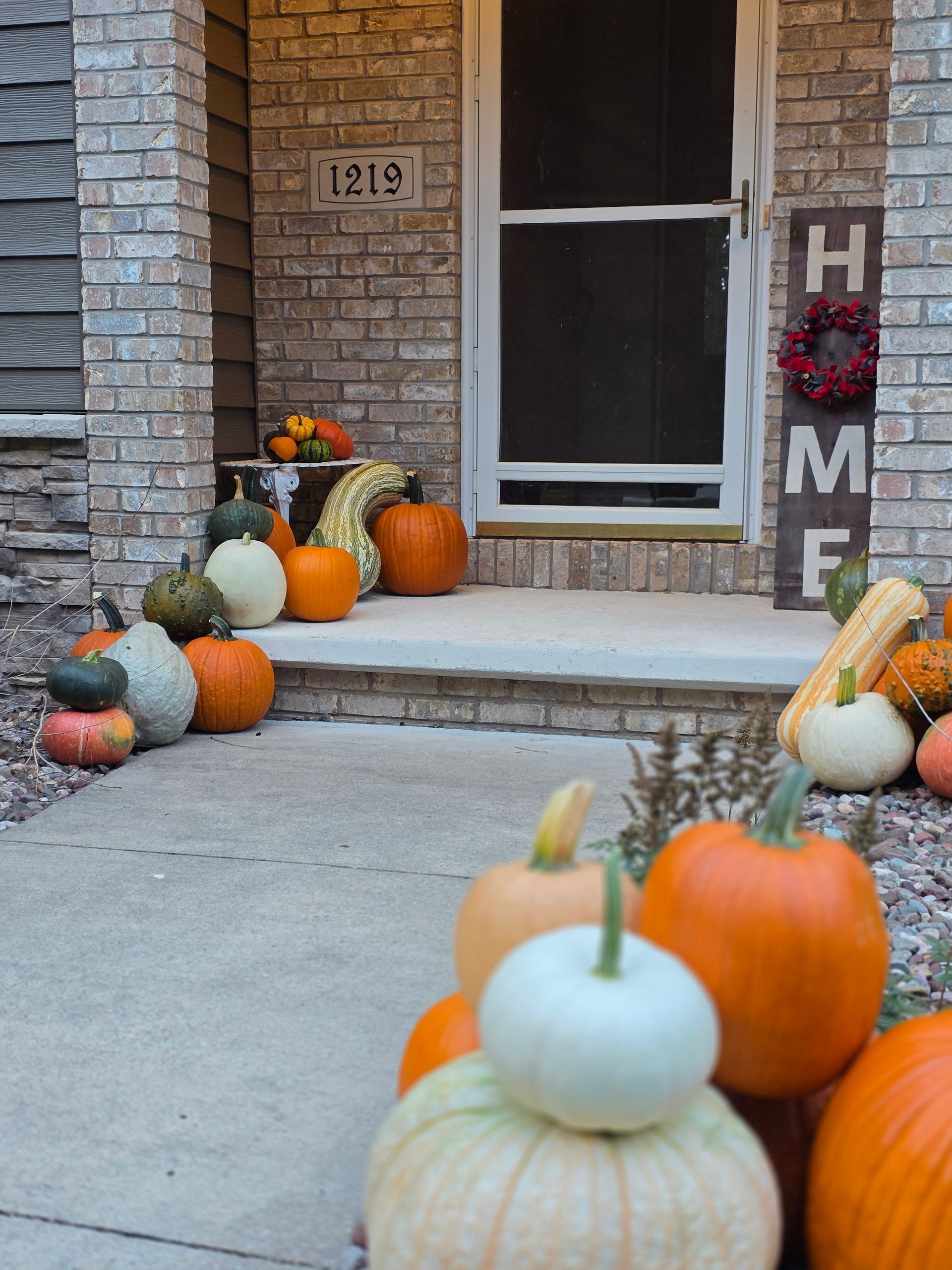 Fall porch decorated with pumpkins of various colors; a 