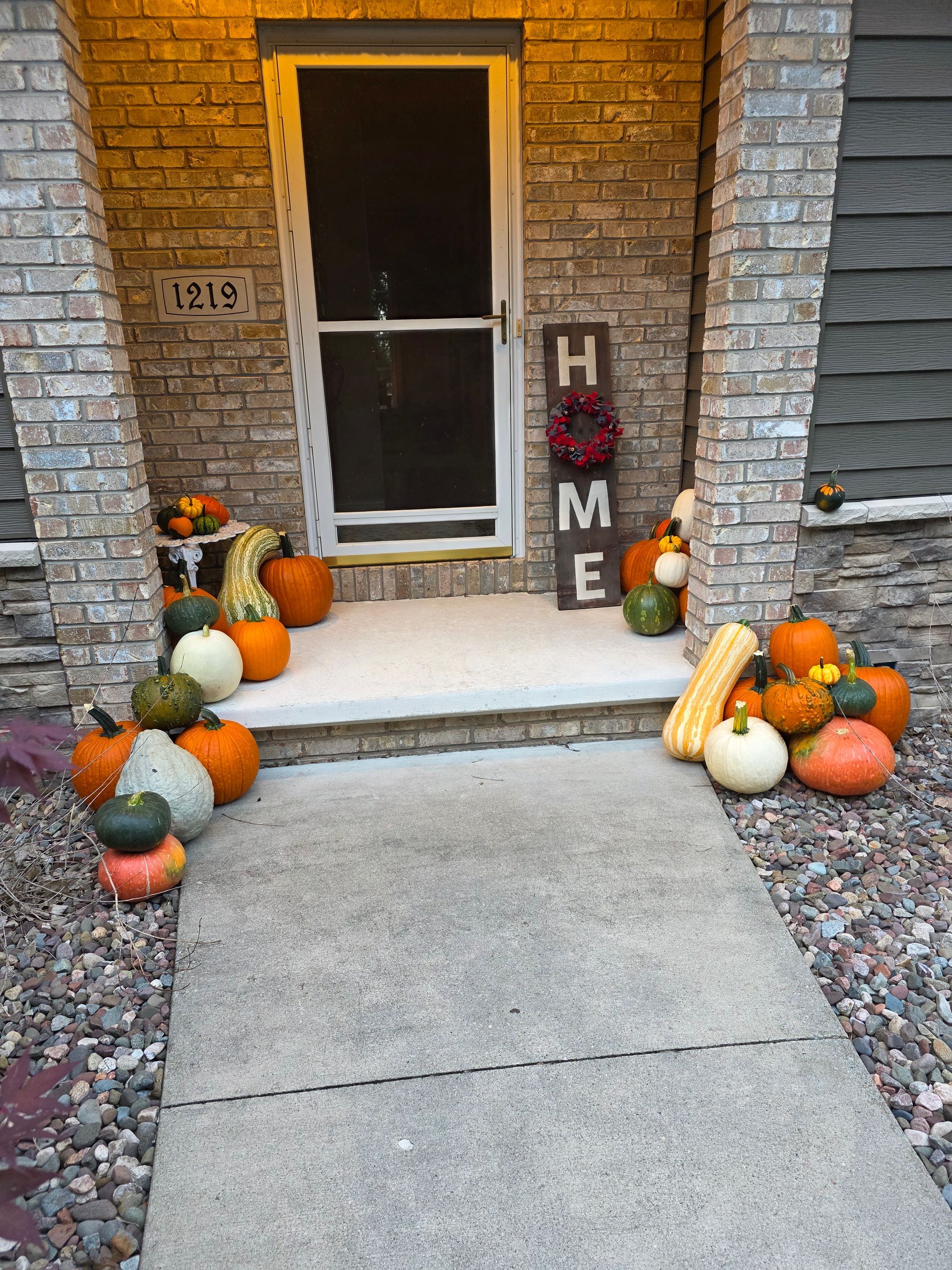 A fall-decorated porch with pumpkins, gourds, and a 