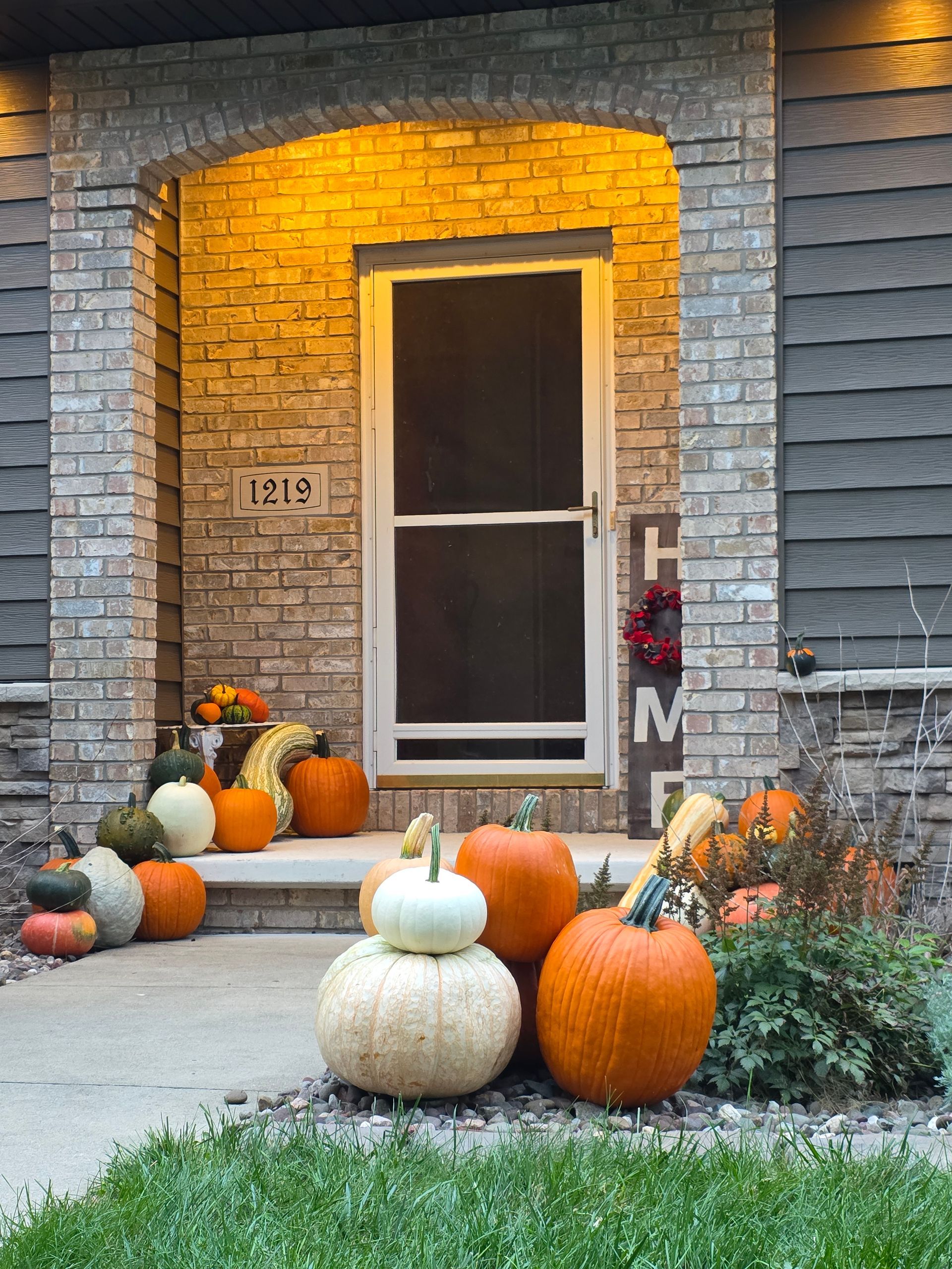 Fall porch decorated with pumpkins and foliage in front of a house.
