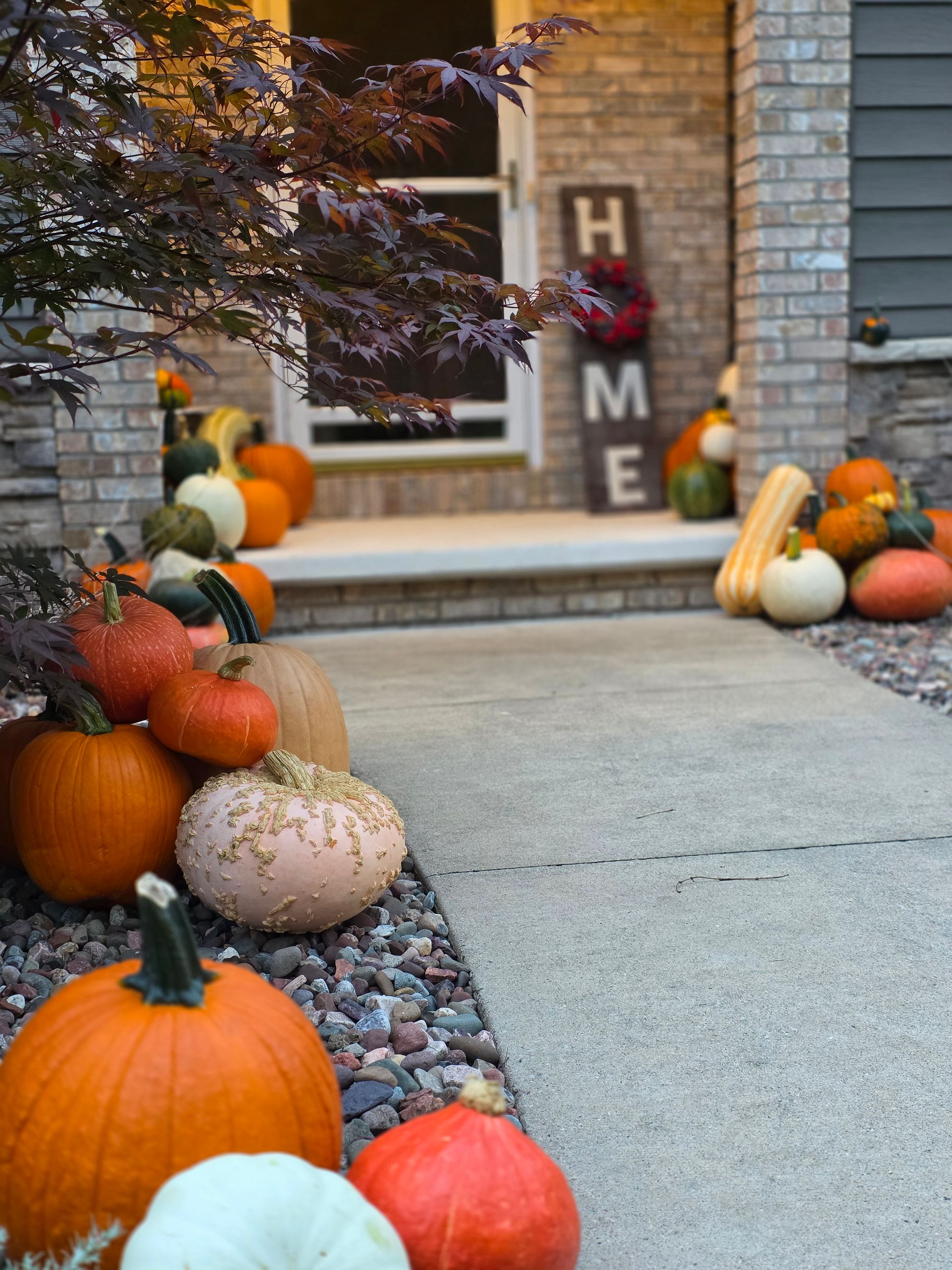 Pumpkins and gourds decorate a front porch, with a 