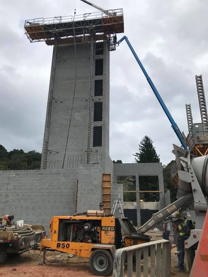 Construction site: Tall gray concrete structure with a boom lift pouring concrete.