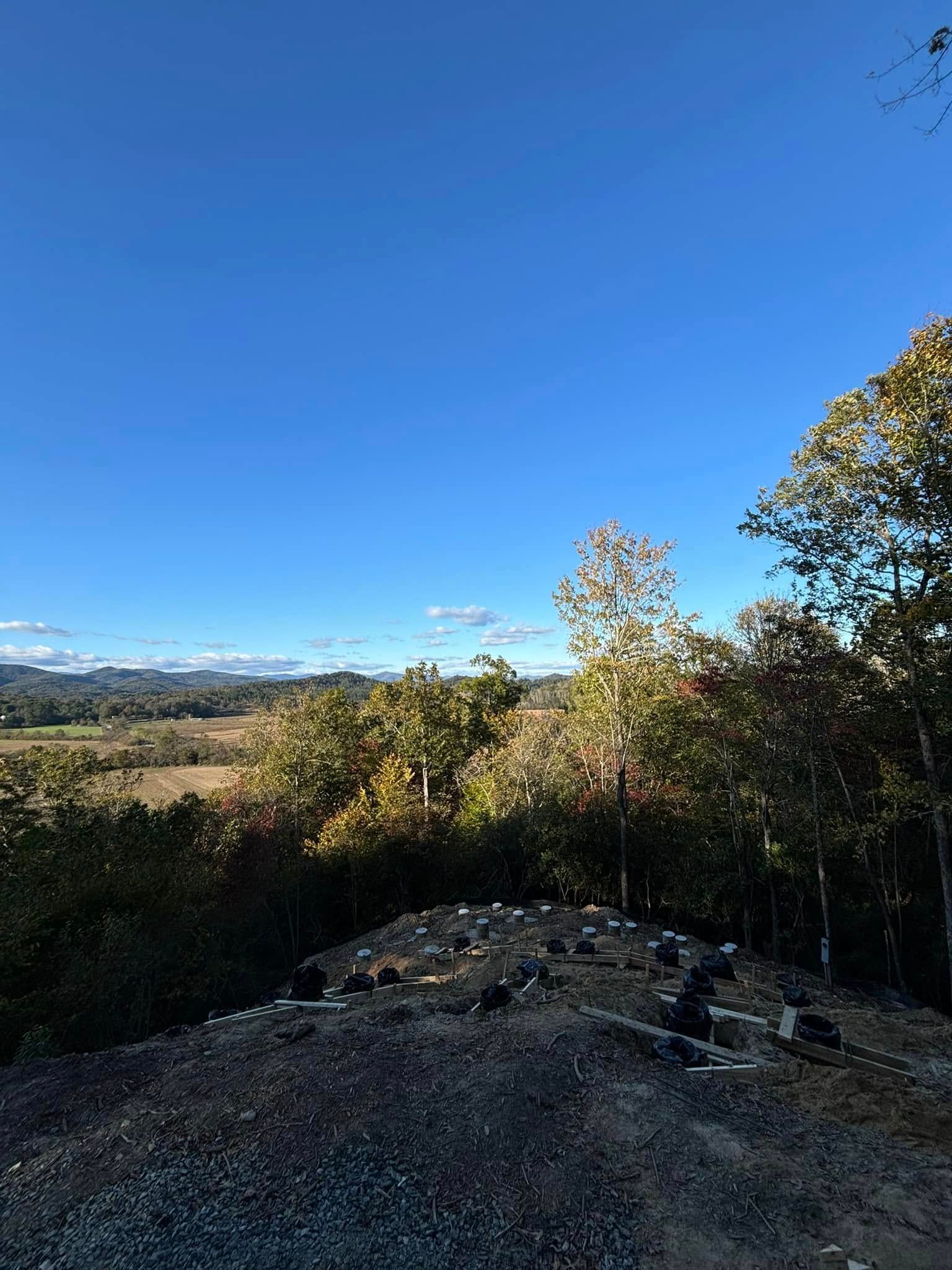 Blue sky over a landscape of trees and a gravelly foreground.