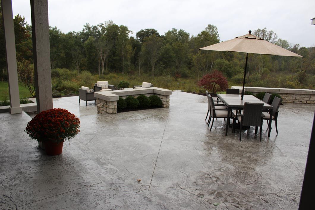A patio with a table and chairs and an umbrella on a rainy day.