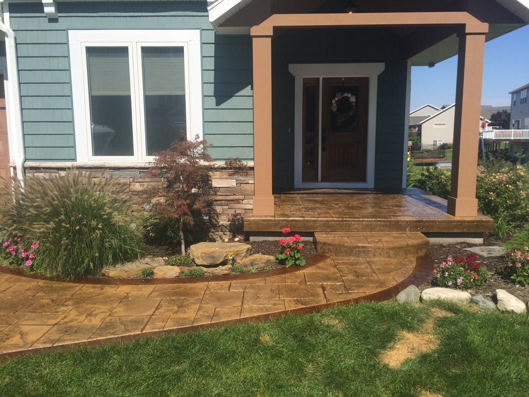 A house with a porch and a concrete walkway in front of it.