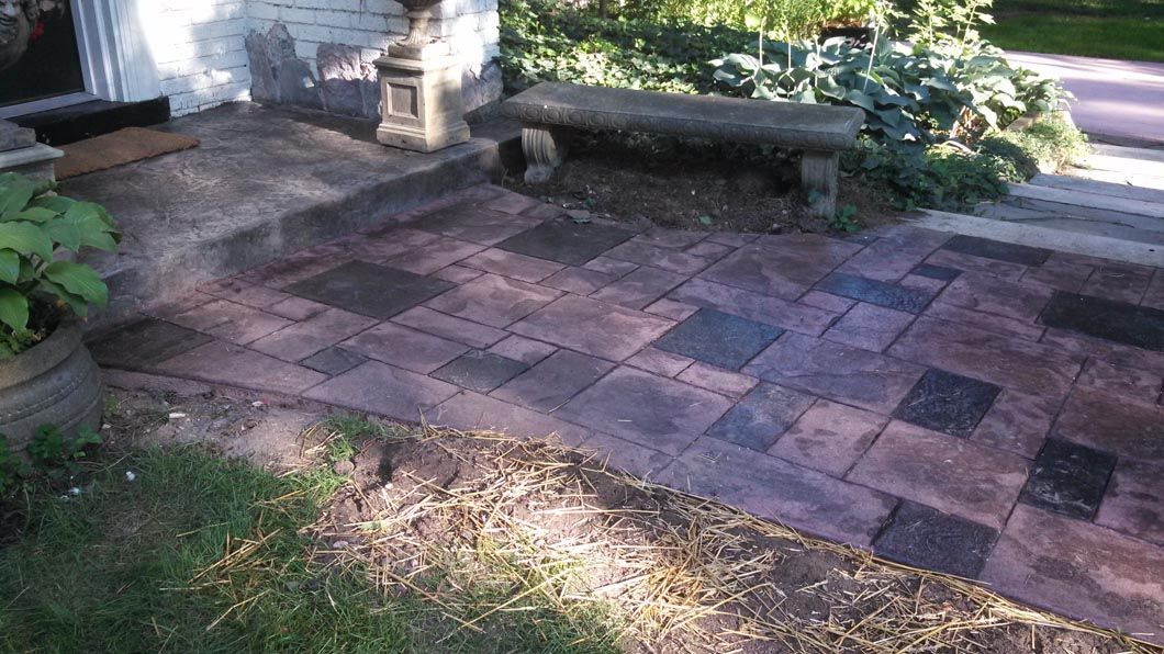 A brick walkway with a bench and steps leading to a house.