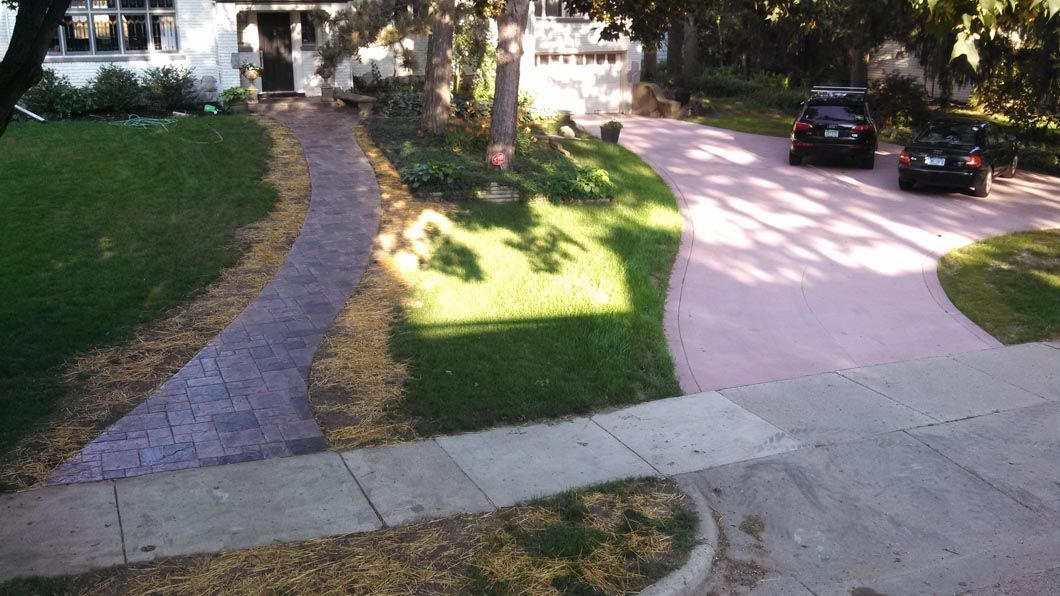 Two cars are parked in a driveway next to a sidewalk.