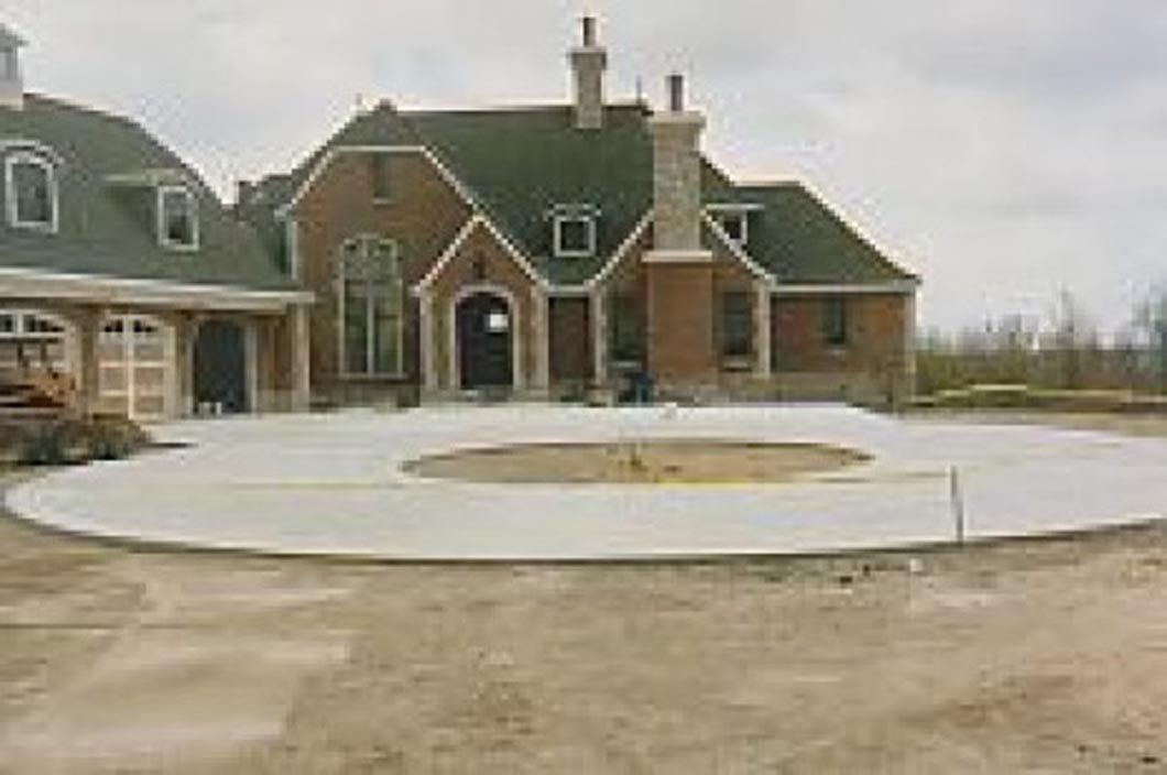A large brick house with a circular driveway in front of it.
