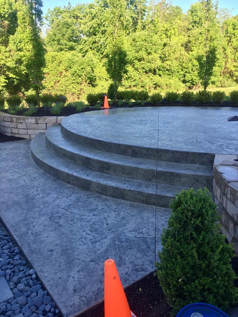 A concrete patio with stairs and a cone in the foreground.
