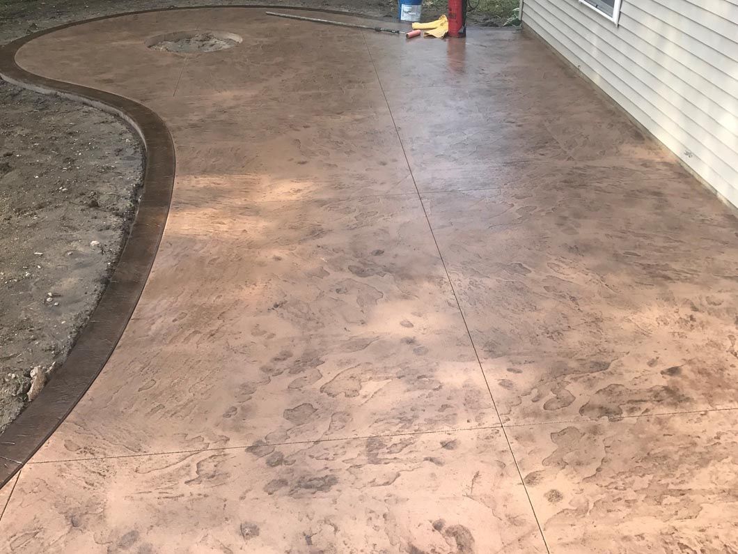 A concrete walkway leading to a house with a curved border.