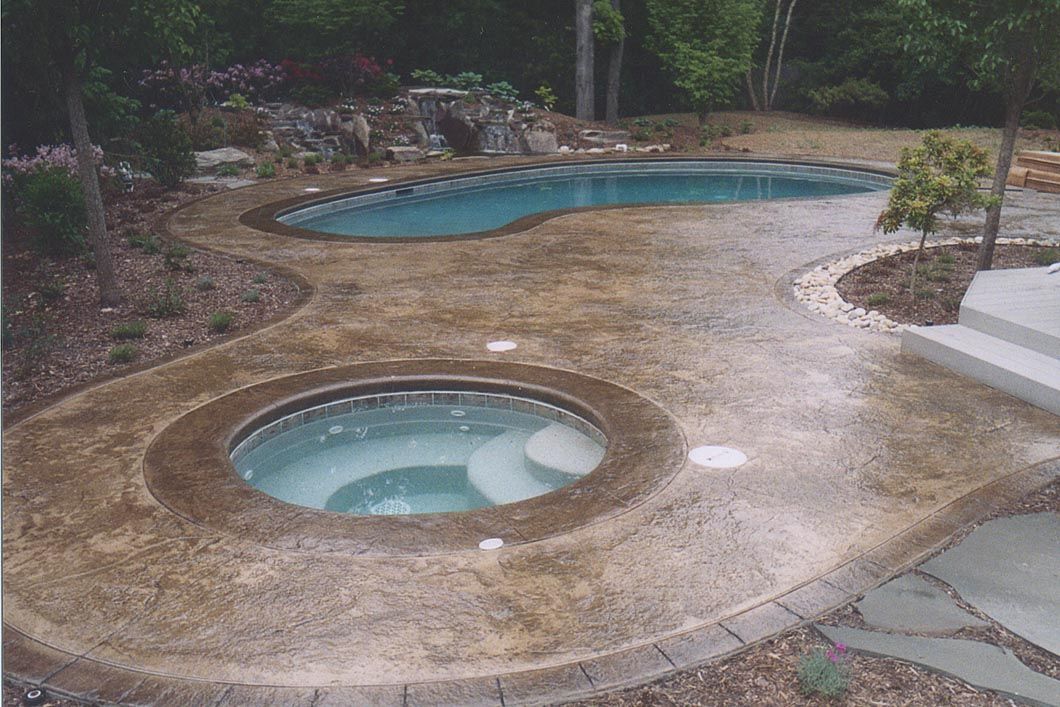 A swimming pool with a hot tub in the middle of it.