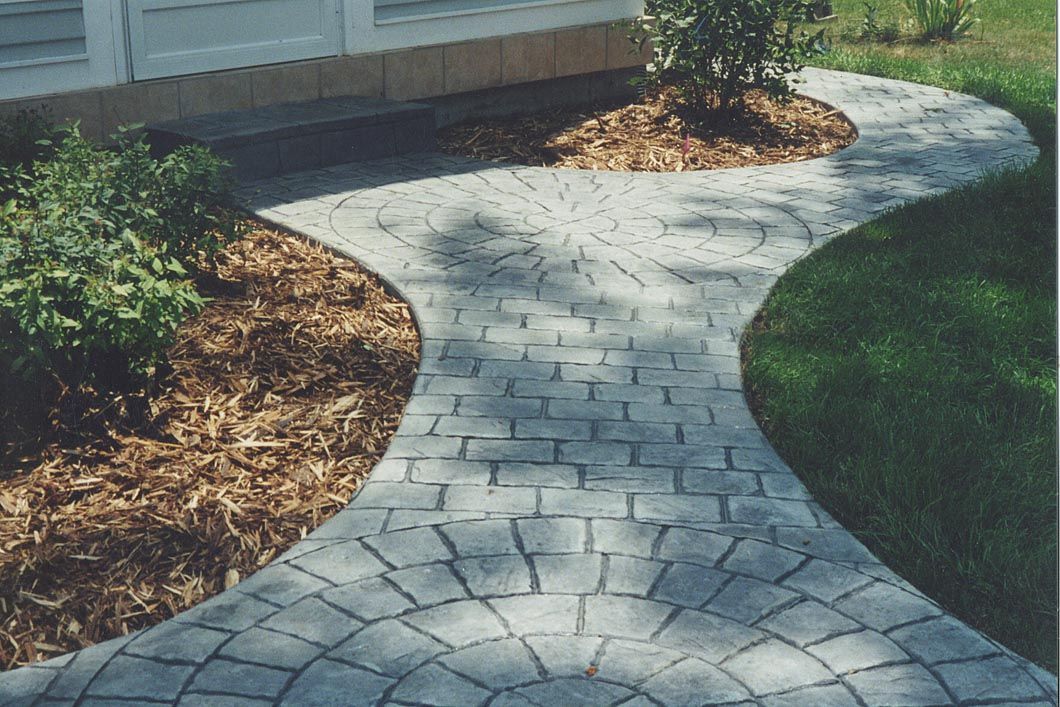 A brick walkway leading to a house with a circular design